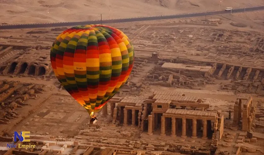 Hot air balloons flying over Luxor at sunrise casting shadows on the West Bank and Nile River