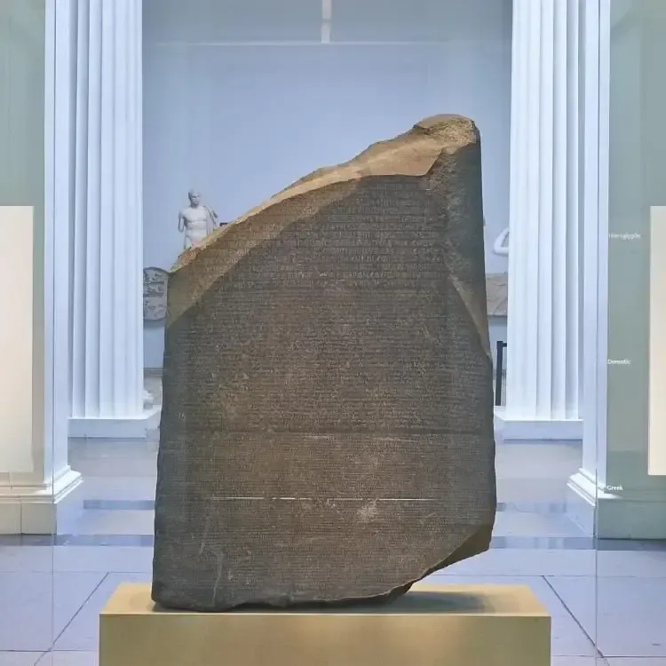 La piedra de Rosetta expuesta sobre un pedestal en una sala de museo con columnas blancas