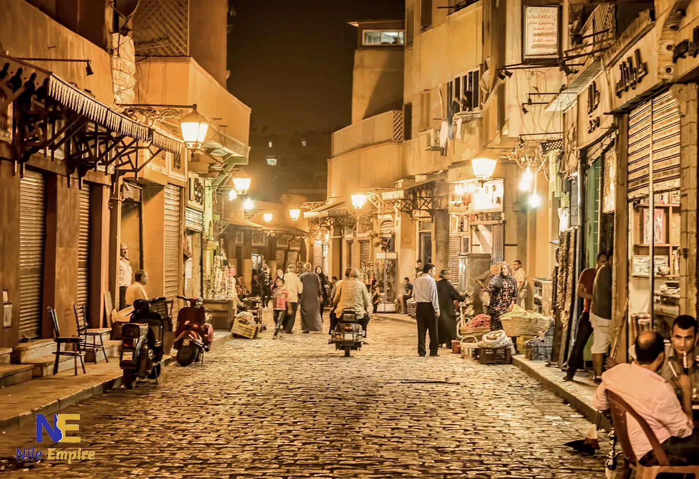 Calle al-Muizz (El Moez) en El Cairo histórico, iluminada de noche con farolas, tiendas y paseantes