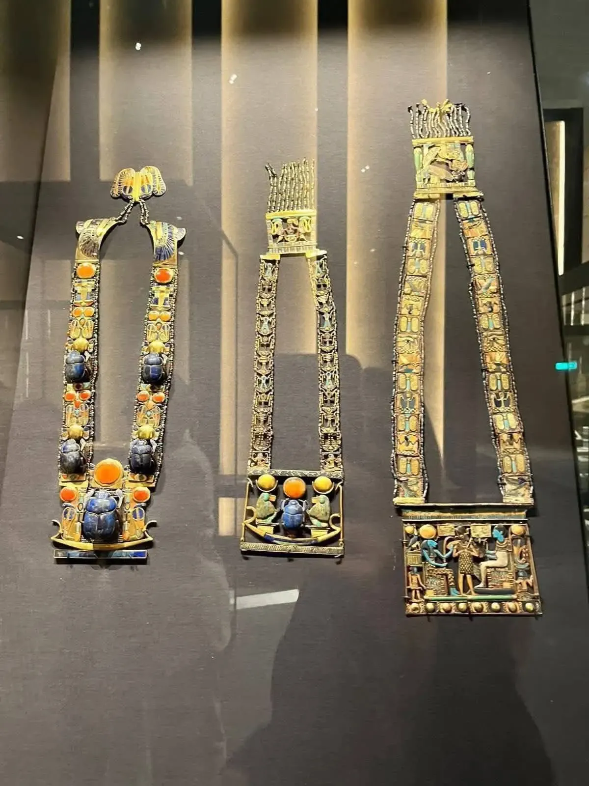 Tres pectorales de oro de Tutankamón con escarabajos de lapislázuli e incrustaciones de colores en una vitrina