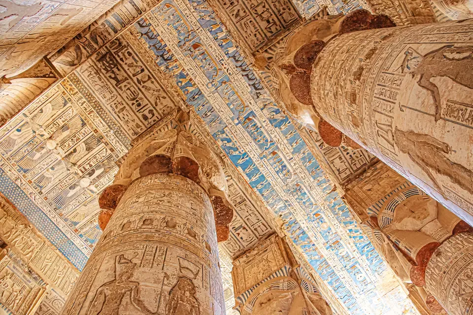 Columnas talladas con capiteles con el rostro de Hathor y franjas de jeroglíficos pintadas en el techo del templo de Hathor en Dendera