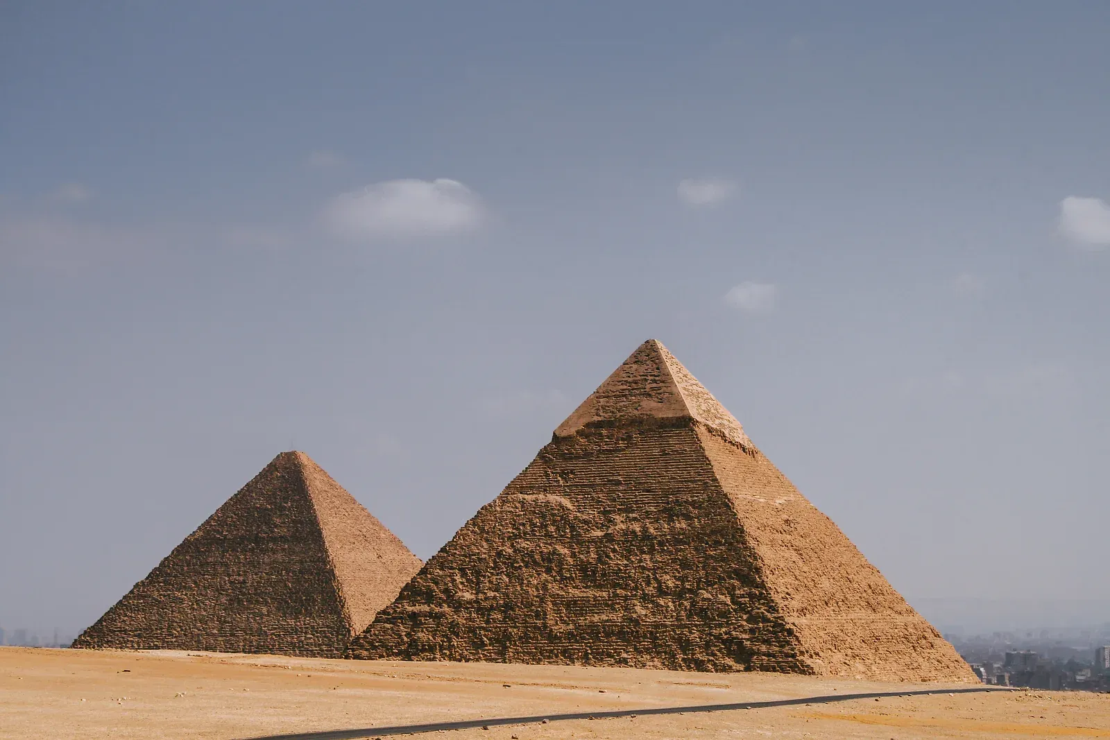 Two Giza pyramids on the desert plateau, the nearer one still covered with smooth casing stones on its upper section