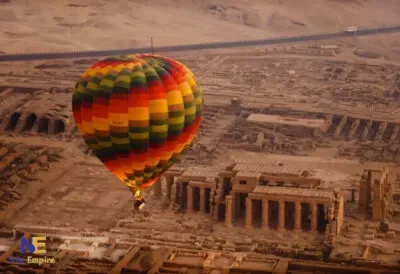 Globo aerostático de franjas de colores volando sobre las ruinas de un templo en la orilla occidental de Luxor