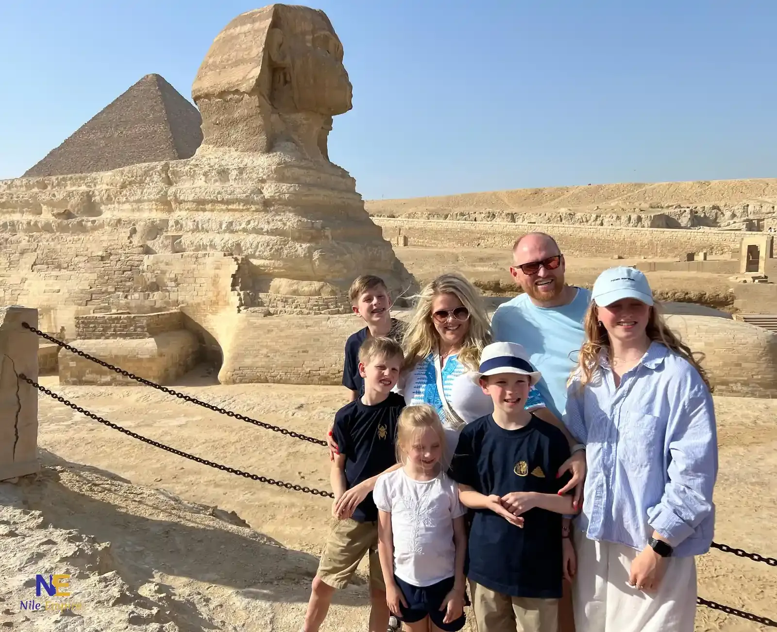 Travellers with children in front of the Great Sphinx of Giza with a pyramid behind
