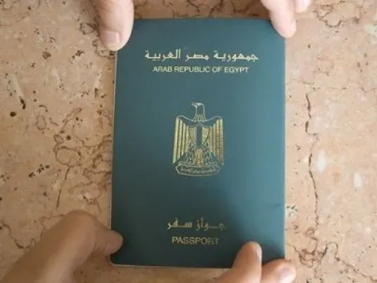 Pasaporte egipcio verde con el escudo de la República Árabe de Egipto, sostenido con las dos manos